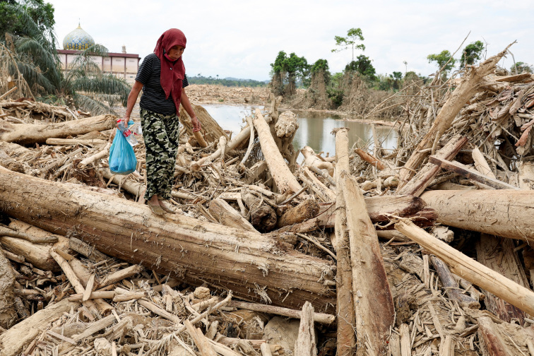 Indonesians climb over logs in walk to aid centre as flood deaths rise over 900